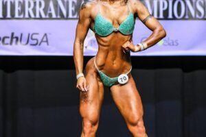 Olena Starodubets posing and smiling on the wellness IFBB stage