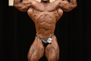 Ahmed Elsadany flexing front double biceps on a bodybuilding stage