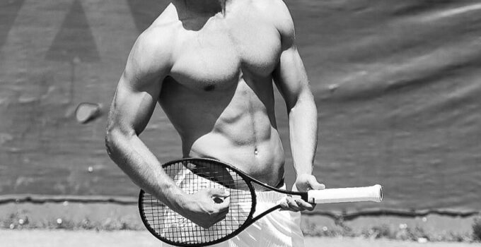 Edoardo Santonocito standing shirtless on a tennis court with a tennis racket in his hand