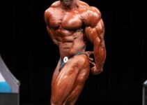 Alexis Rivera Rolon doing a side triceps pose on a bodybuilding stage, looking confident and impressive