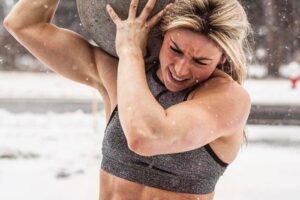 Tiffany Szemplinski carrying a heavy boulder on her shoulders