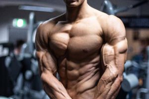 Carlton Loth flexing shirtless in the gym