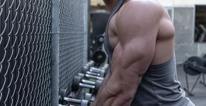 Chris Clark holding dumbbells looking muscular