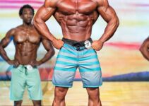 Diogo Montenegro posing on the Men's Physique stage, showcasing his ripped chest, arms, and midsection