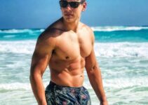 Gabriel Arones standing shirtless on the beach with black sunglasses, looking fit and strong