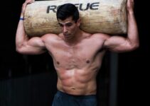 Garret Fisher shirtless, carrying heavy log over his head