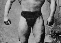 George Hackenschmidt standing shirtless, posing with his lats spread wide, looking muscular and strong