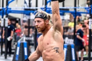 Graham Holmberg lifting a kettlebell over his head during a CrossFit competition