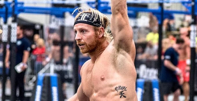 Graham Holmberg lifting a kettlebell over his head during a CrossFit competition