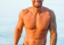 Matt Fox standing shirtless on the beach smiling for the photo, looking fit and lean