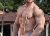 Rafael Rey standing shirtless outdoors with headphones on, looking swole and ripped