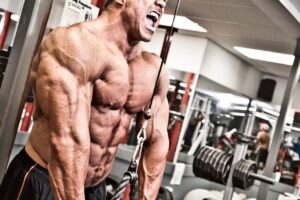 Ron Partlow doing triceps extensions in the gym with a pained expression on his face