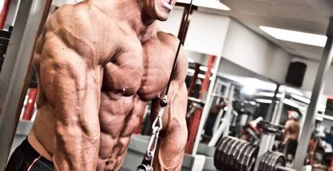 Ron Partlow doing triceps extensions in the gym with a pained expression on his face