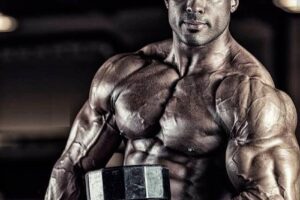 Henri-Pierre Ano lifting a dumbbell while looking at the camera, looking ripped and lean