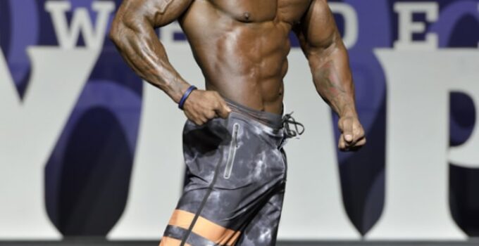 Antoine Williams smiling at the Men's Physique Olympia stage, looking ripped and muscular