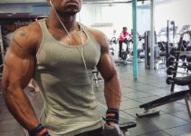 Antonio Mitchell showing his ripped physique in a grey tank top in the gym