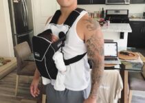 Bart Kwan carrying his child in a front facing baby carrier and smiling at the camera