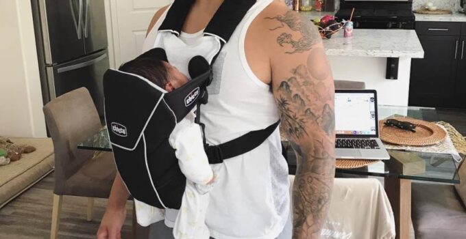 Bart Kwan carrying his child in a front facing baby carrier and smiling at the camera