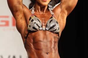 Chloe Sannito flexing her abs on a bodybuilding stage