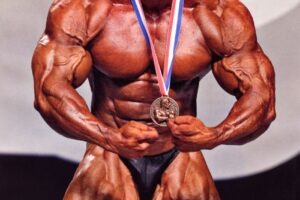 Dennis Wolf flexing on the stage with a medal around his neck