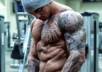 Devin Physique posing shirtless in a grey hat for a photo, looking ripped and muscular