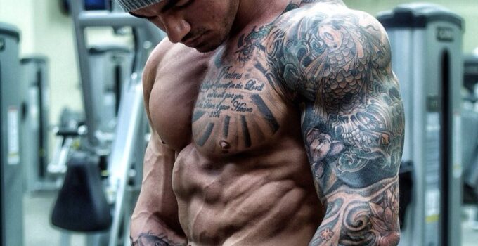 Devin Physique posing shirtless in a grey hat for a photo, looking ripped and muscular