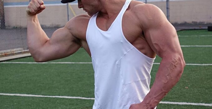 Dylan McKenna flexing his arm wearing a white tank top