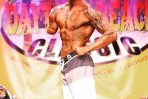 Jared Bullock on stage at a bodybuilding competition.,