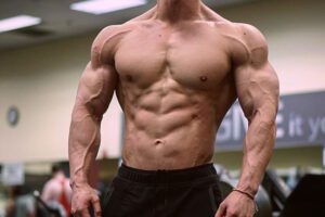 John Nguyen posing in the gym showing off his abs.