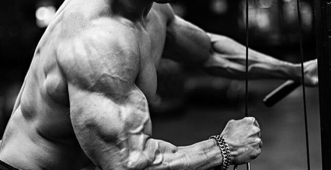 Julian Smith training shirtless with cables in a gym looking ripped