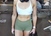 Lauren Tickner holding weight plates and smiling for a photo in a gym