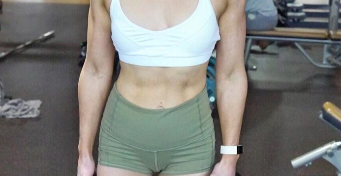 Lauren Tickner holding weight plates and smiling for a photo in a gym