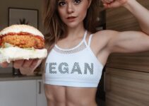 Stefanie Moir posing for a photo with a vegan burger in her hand looking fit and healthy